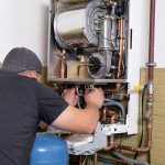 Plumber performs power flush on boiler